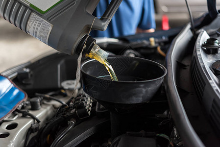 汽车修理技工或服务人员在车库中填充新鲜润滑油图片