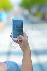女人在街上用智能手机拍照图片