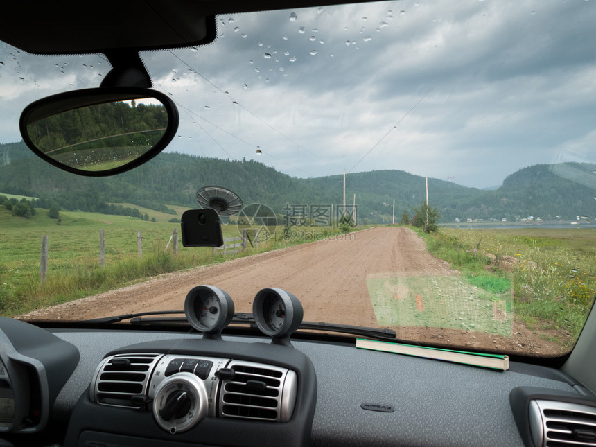通过一辆汽车挡风玻璃看到通往村庄的道路图片