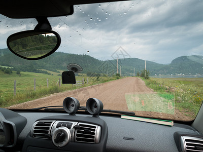 通过一辆汽车挡风玻璃看到通往村庄的道路图片