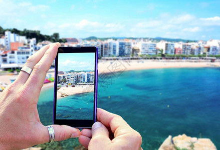 在布拉内斯镇的布拉瓦海岸拍照时查看手机显示屏手里拿着手机拍照专图片