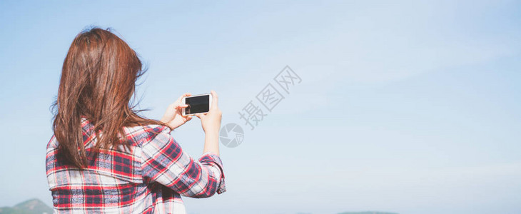 有个女人在海滩的地平线上用智能手机相拍照图片