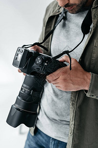 照片制室里用数字摄影相机拍摄的男摄影专业摄影师在灰背景图片