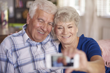 在手机上做自拍的年长夫妇多亏了数字技术图片