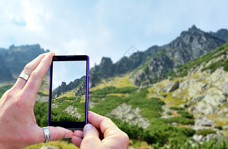 在大自然中拍摄风景照片时查看手机显示屏手里拿着手机拍照专图片