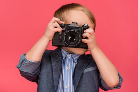 模糊的画面显示孩子拿着照相机在粉背景图片