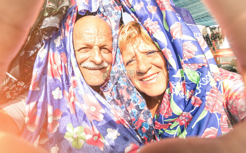 快乐的老夫妇在周游世界的服装市场自拍图片