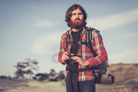 英俊的男背包客带着相机在荒野中追随他对摄影的爱好和热情图片