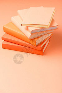 橙色表面上的一堆彩色精装书背景图片