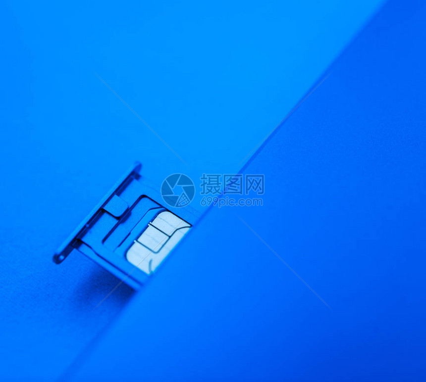 蓝色背景下新智能手机电话移动设备内的微型SIM卡图片