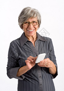 戴眼镜的高级女使用手机站着输入文字或号码以拨打电话图片