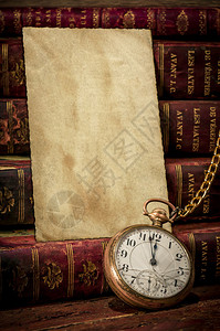 带有旧相纸纹理的复古木桌书籍和旧袖珍时钟背景图片