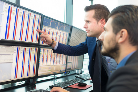 买卖股票的商人股票交易员在多个电脑屏幕上查看图表指数和字同事们在交易图片