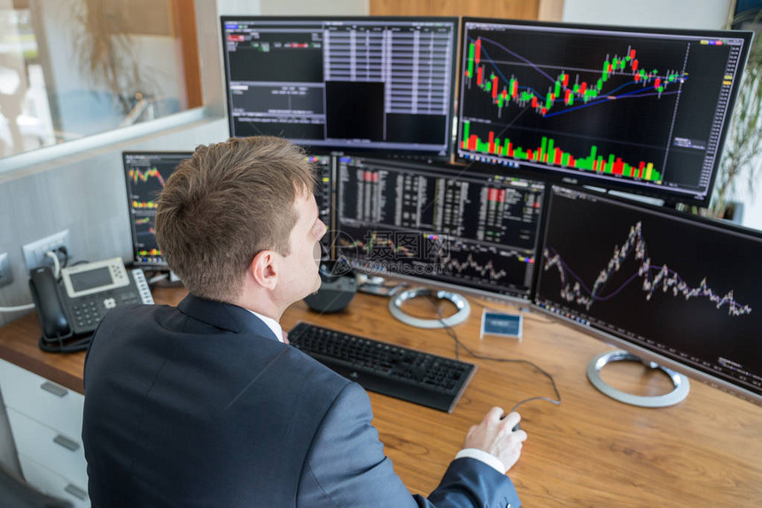 商人交易股票股票交易员在现代交易办公室的多个电脑屏幕上查看图表指数图片