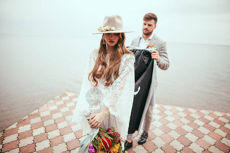 穿着婚纱帽子和新郎的有吸引力新娘图片