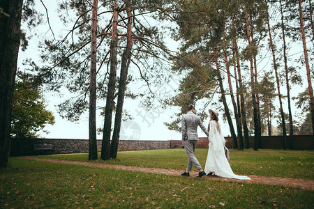 穿着婚纱的新娘和新郎手牵在公园里散步图片