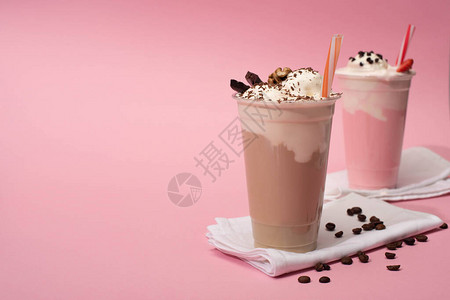 粉红色背景餐巾纸上一次巧克力和草莓奶昔图片