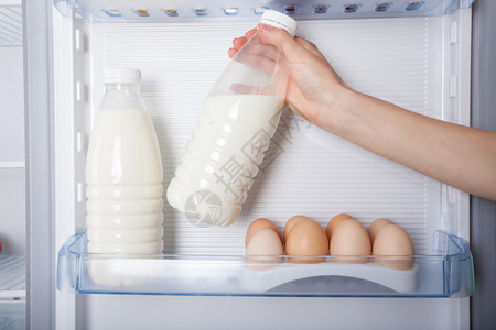 伸手去拿冰箱里的一瓶牛奶图片