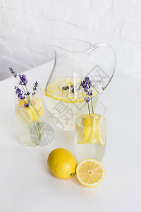 清凉的柠檬水在杯子和桌上罐子上图片