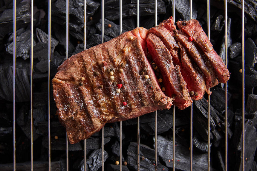 最顶端有新鲜烧烤美味牛排鲜熟的烤肉和调味料在黑煤上图片
