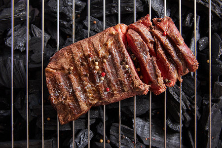 最顶端有新鲜烧烤美味牛排鲜熟的烤肉和调味料在黑煤上图片