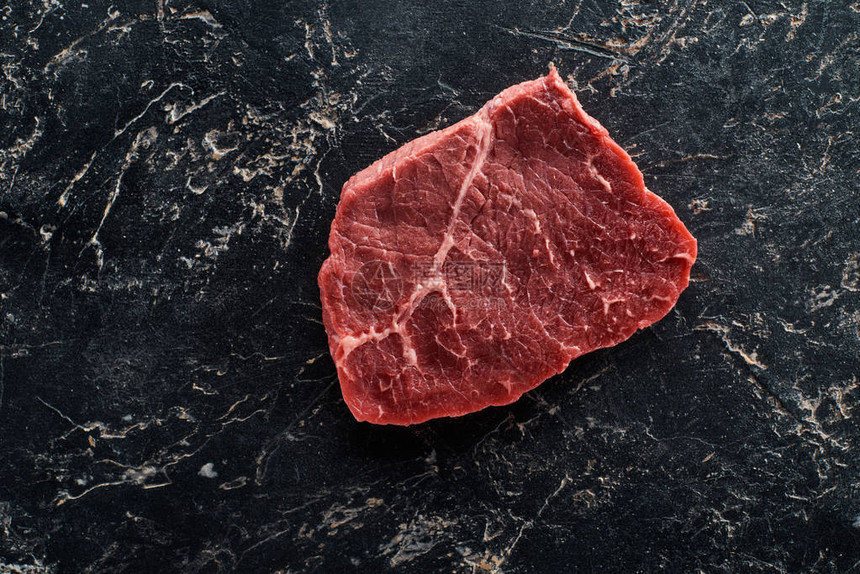黑色大理石背景上未煮熟的牛里脊肉的顶部视图图片