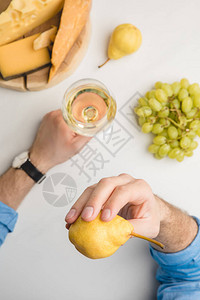 用梨子和葡萄酒玻璃葡萄和白制木板上不同种类的乳酪图片