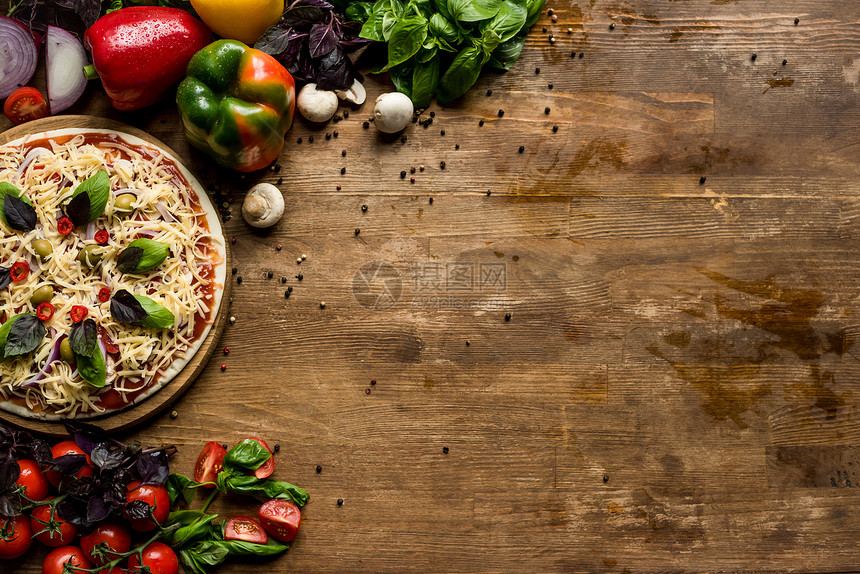 木板上带奶酪和新鲜原料的原始自制披萨顶端图片