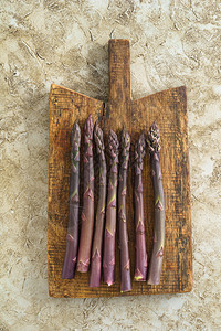 木板上新鲜的未煮过的紫色芦笋茎图片