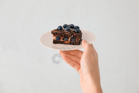 妇女拿着盘子和蓝莓巧克力蛋糕的浅底片图片