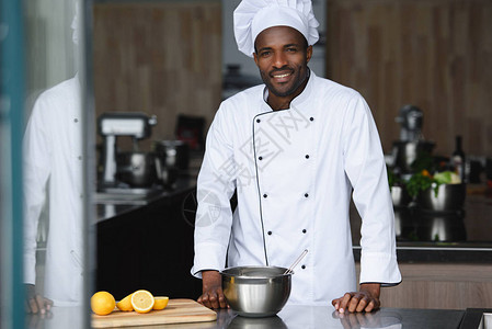 英俊的非洲裔美国厨师站在餐厅厨房的图片