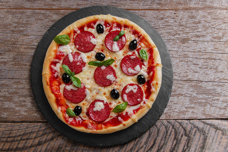 黑石头上的意大利腊肠番茄和奶酪披萨图片
