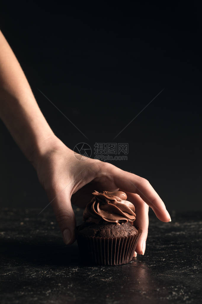 近距离部分观察人类手拿着美味巧克力蛋糕黑图片