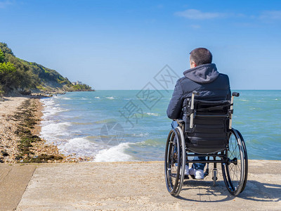 在沙滩坐轮椅的残疾青年男子图片