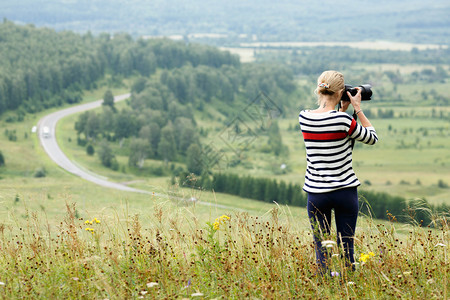 女摄影师在山顶上拍摄山丘的照片图片