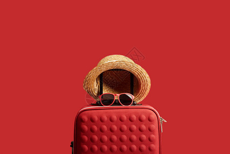 红色彩旅行袋上面有草帽和墨镜图片