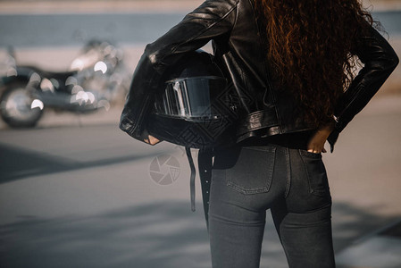 妇女戴头盔背着摩托车站立在图片