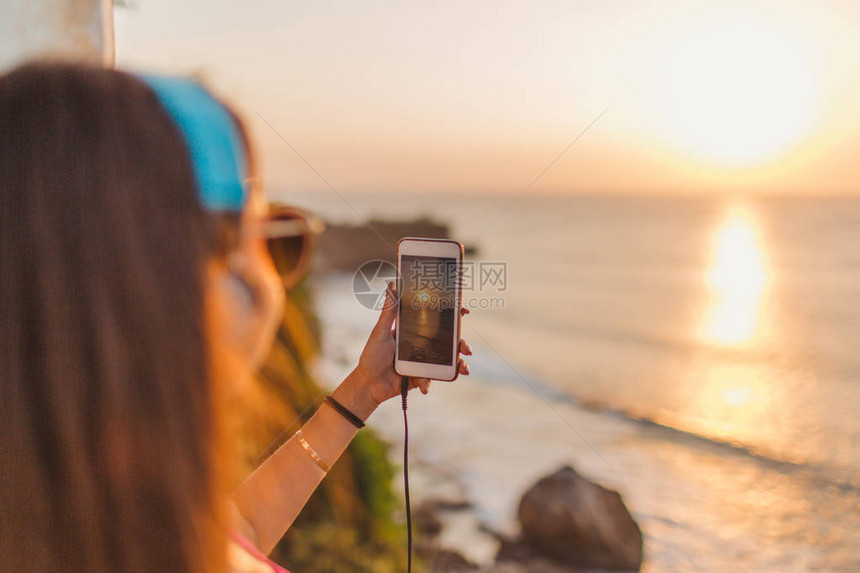 在日落时拍摄海洋照片的耳机中女图片