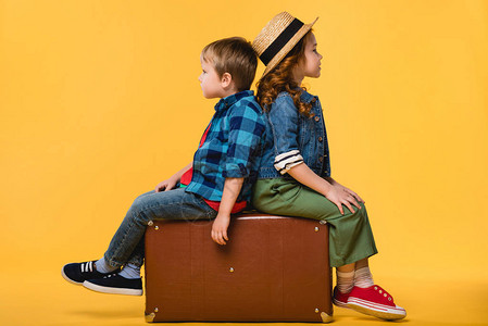 儿童坐在黄色的皮衣手提箱上被孤立在图片