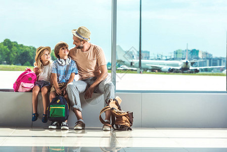 在机场等待登机的微笑的父亲和小孩图片