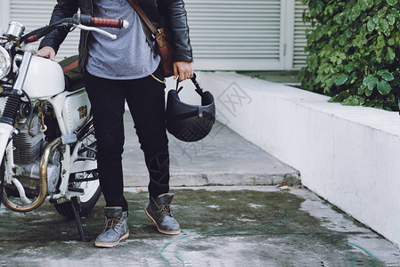时尚男子手持头盔站在古老的摩托车图片