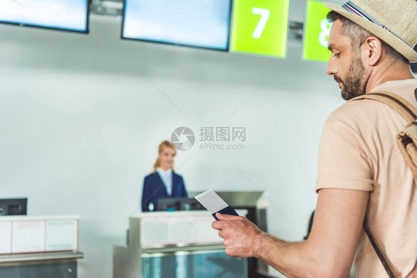 持有护照和机票的男子在机场办公桌前等待检查时手图片