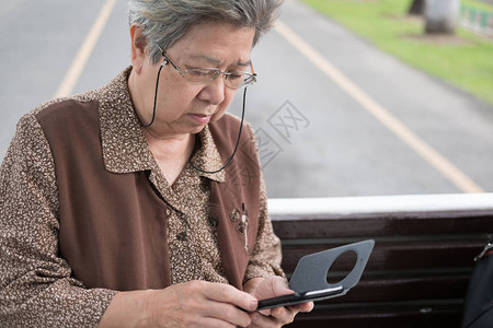 亚洲老妇人在城市公交车上拿着智能手机图片