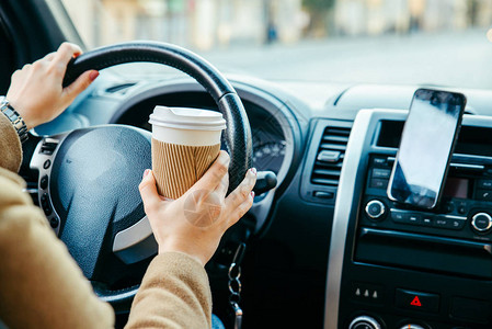 妇女驾驶汽车和喝咖啡电话导航图片