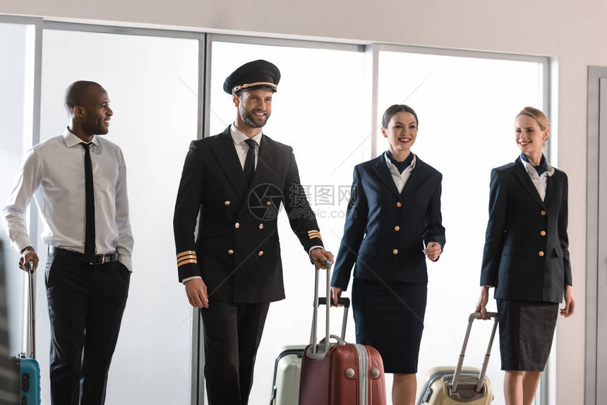 快乐的航空人员团队走在机场滑行图片