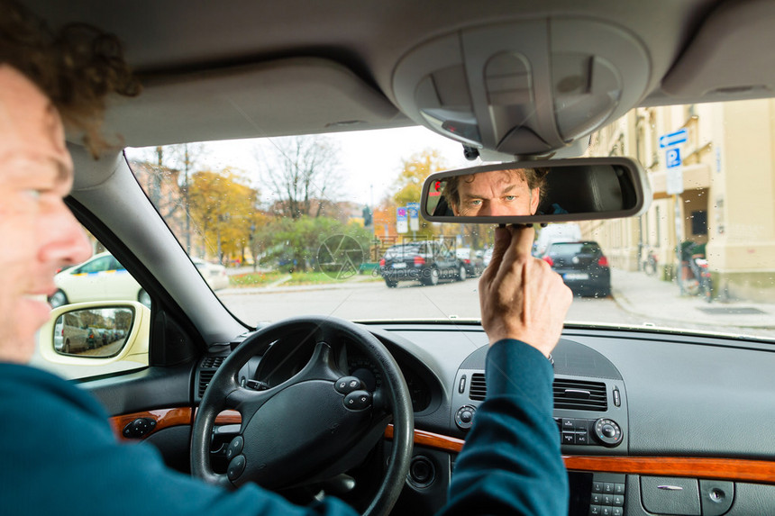 经验丰富的出租车司机正在其出租车的后视镜中寻找图片