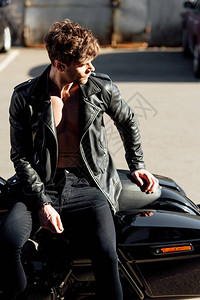 年轻摩托车手坐在摩托车图片