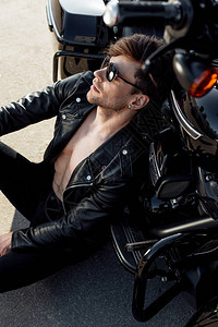 肌肉英俊的男人坐在地上靠在摩托车上图片