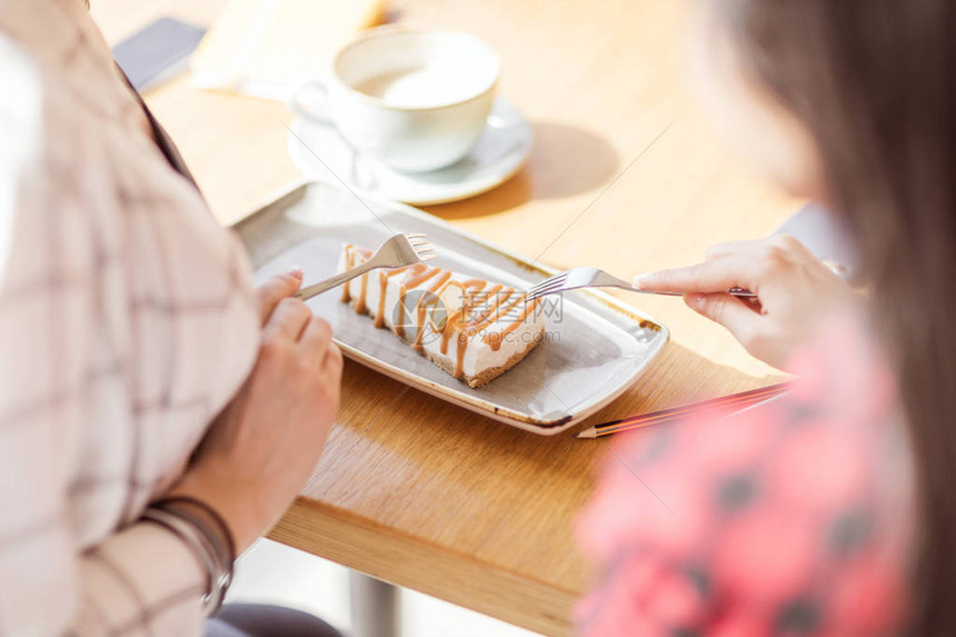 年轻女孩在咖啡馆用叉子吃甜点图片
