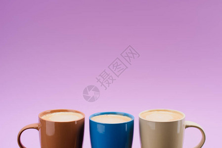 在紫色上隔绝的彩色咖啡杯中图片